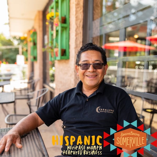 Smiling man in sunglasses and a Casa Luna shirt sitting at an outdoor table.