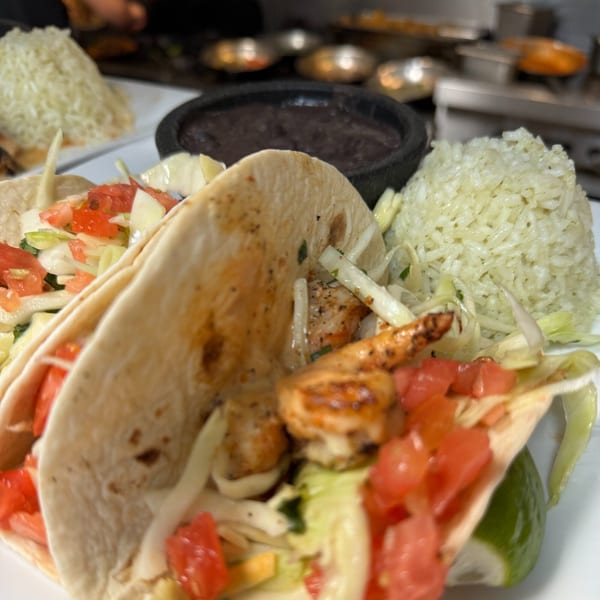 Two shrimp tacos with rice and black beans on a white plate at Casa Luna Mexican Cuisine.