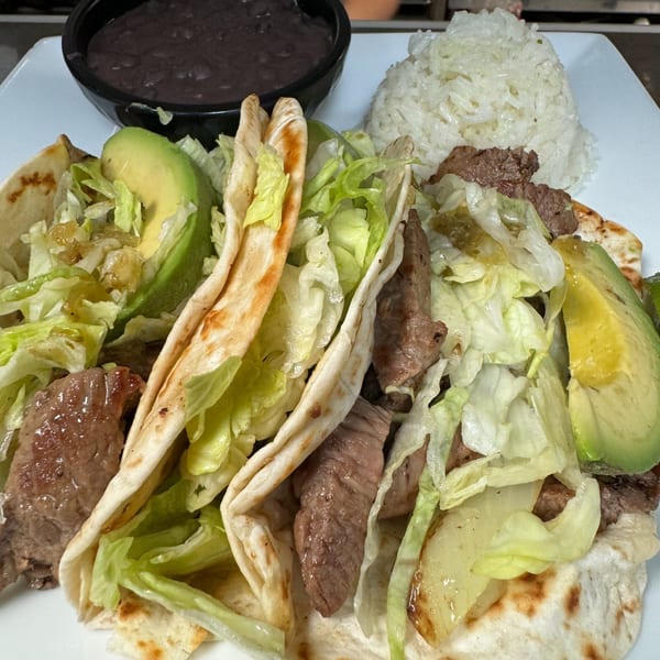 Three Casa Luna Mexican Cuisine steak tacos with lettuce, avocado, rice, and black beans.