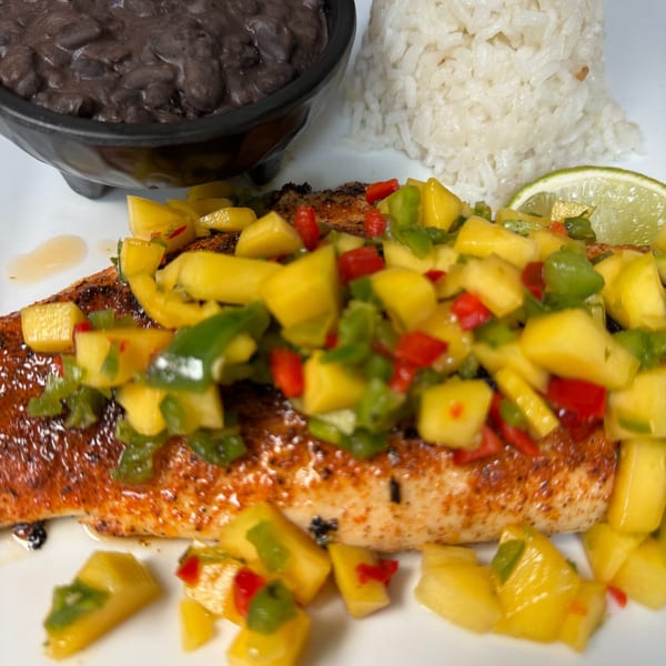 Grilled fish topped with mango salsa, served with white rice and a side of black beans.