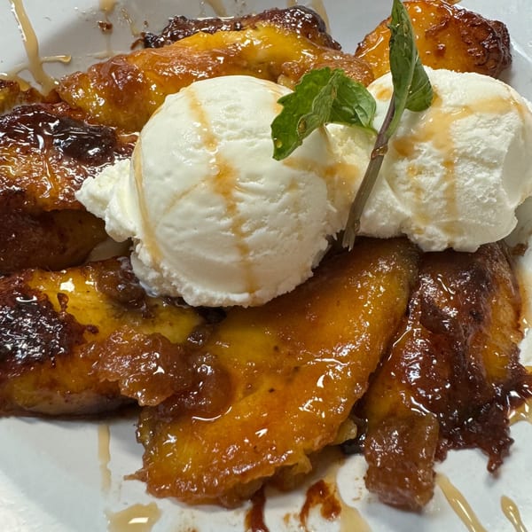 Caramelized plantains topped with vanilla ice cream, drizzled with syrup and garnished with mint.