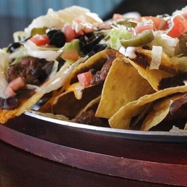 A close-up of Casa Luna's loaded nachos with cheese, beans, lettuce, tomatoes, olives, and jalapeños.