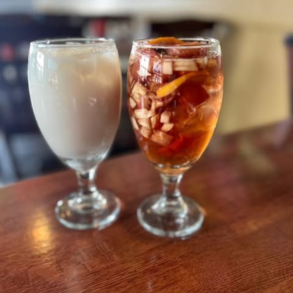 Two drinks on a wooden table, one white and one red with fruit, at Casa Luna Mexican Cuisine.