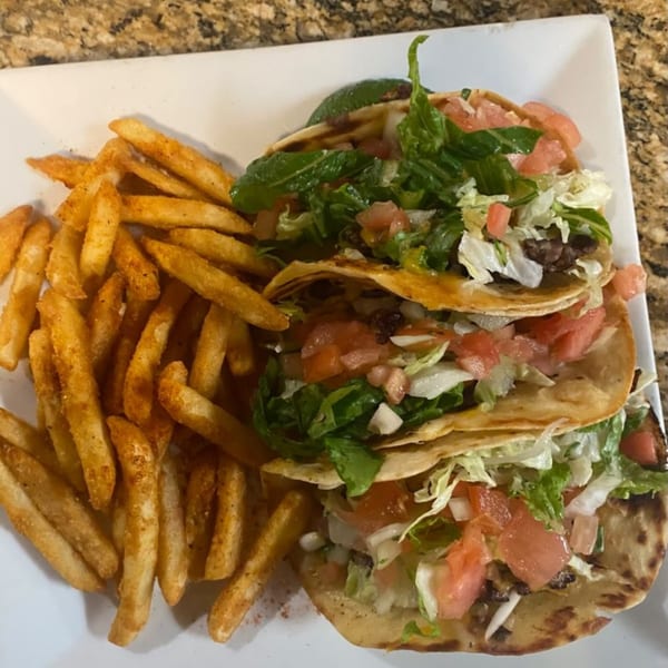 Three Casa Luna Mexican Cuisine tacos with meat, lettuce, and tomatoes, served with a side of fries.