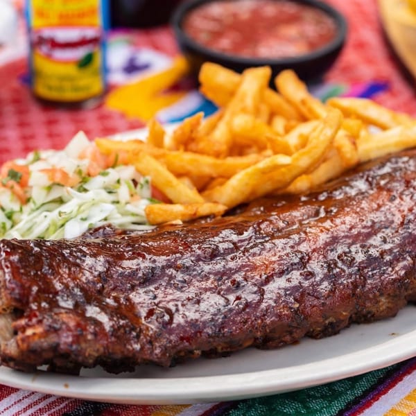 Casa Luna's BBQ ribs with fries and coleslaw, alongside salsa and hot sauce.
